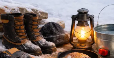 Winter homestead tools including insulated boots, gloves, cast iron skillet, and lantern used daily during cold weather