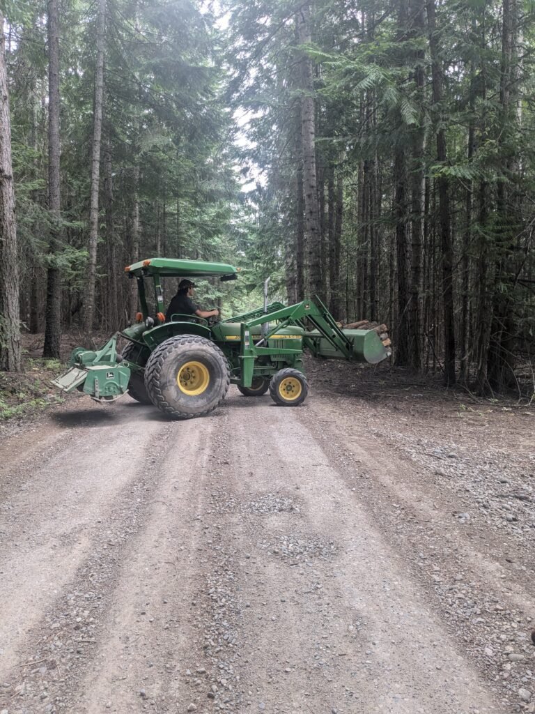 Teenage son helping with homestead chores by hauling firewood on the John Deere tractor