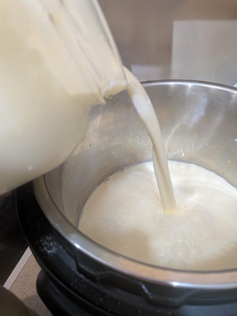 Pouring a gallon of fresh raw milk into the instant pot to make yogurt.