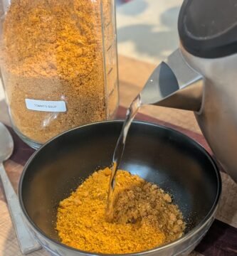 An instant kettle of hot water being poured into a bowl of freeze dried tomato soup