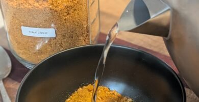 An instant kettle of hot water being poured into a bowl of freeze dried tomato soup