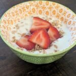 Homemade yogurt made in an instant pot and poured into a bowl with granola and sliced fresh strawberries on top
