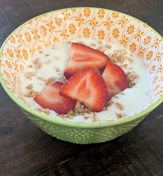 Homemade yogurt made in an instant pot and poured into a bowl with granola and sliced fresh strawberries on top