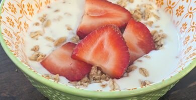 Homemade yogurt made in an instant pot and poured into a bowl with granola and sliced fresh strawberries on top