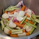 A large stainless steel stock pot with homemade chicken bone broth