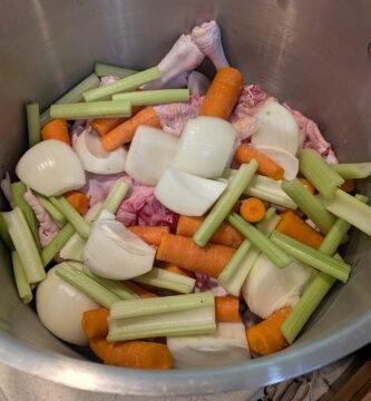 A large stainless steel stock pot with homemade chicken bone broth