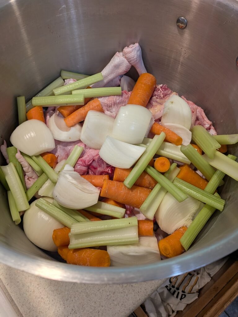 A large stainless steel stock pot with homemade chicken bone broth