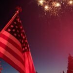 American flag flying with fireworks in the background