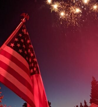 American flag flying with fireworks in the background