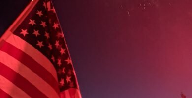 American flag flying with fireworks in the background