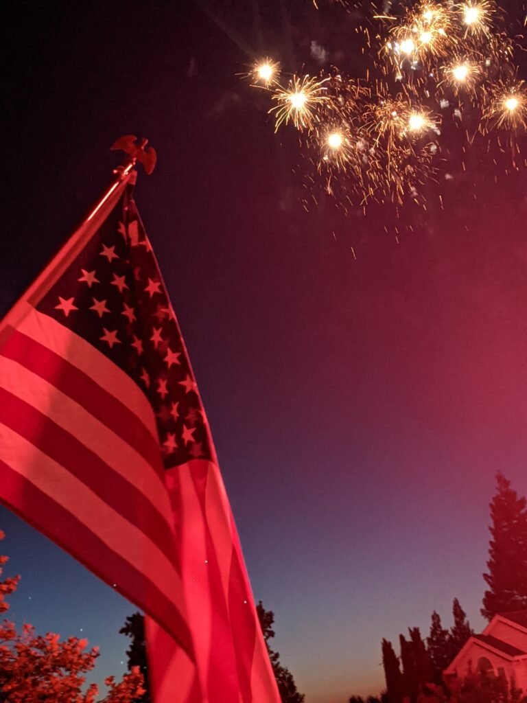 American flag flying with fireworks in the background